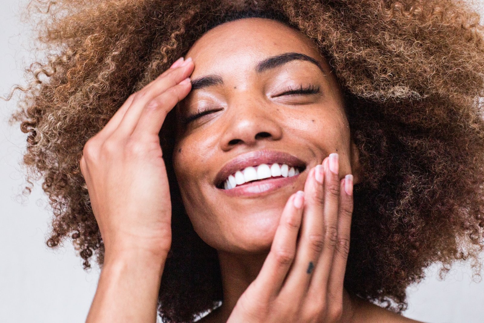 woman with afro smiling and touching face